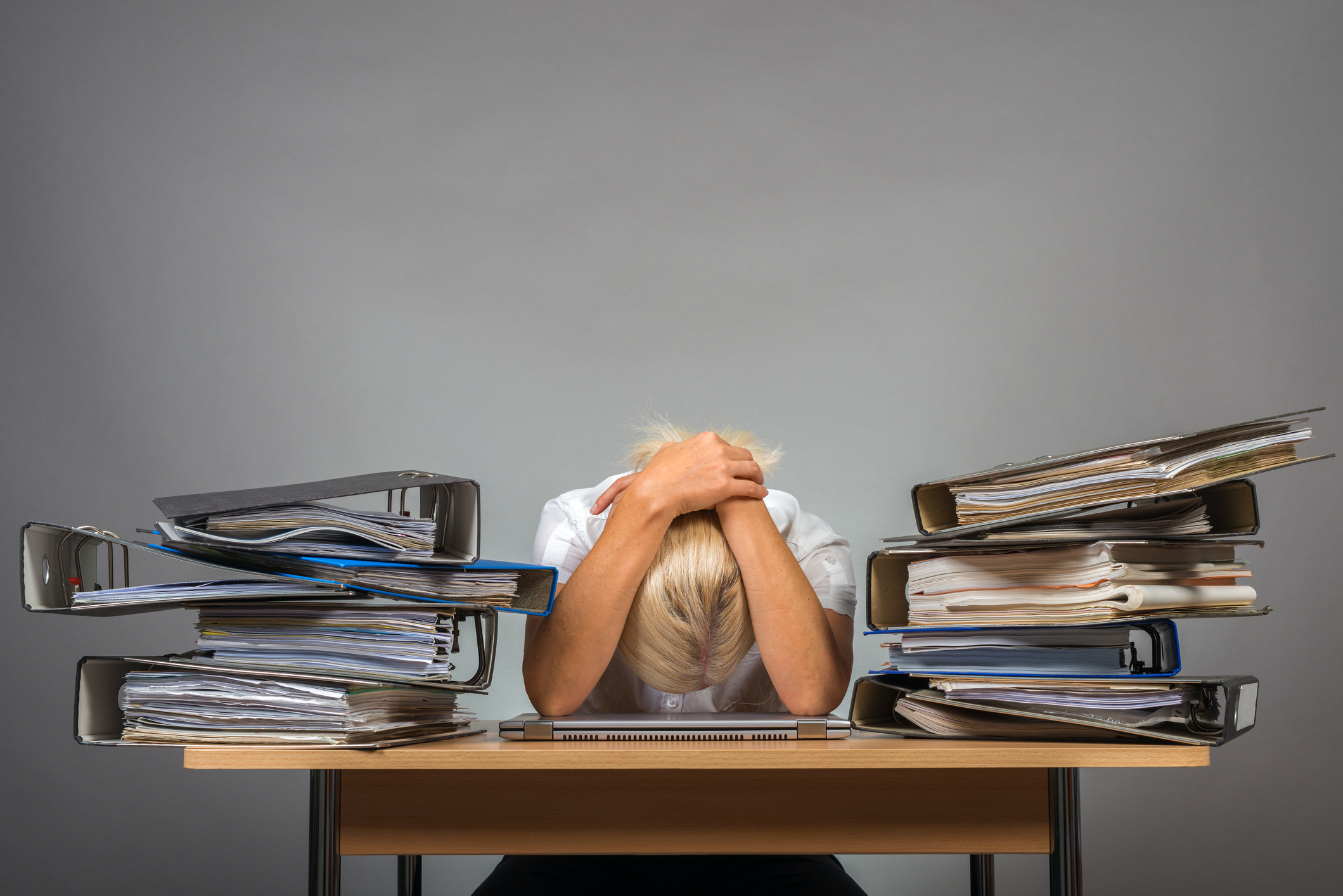 Tired woman on desk surrounded by files